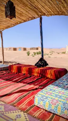 a colorful rug on the floor of a tent in the desert at Camp Ayour Mhamid in Mhamid