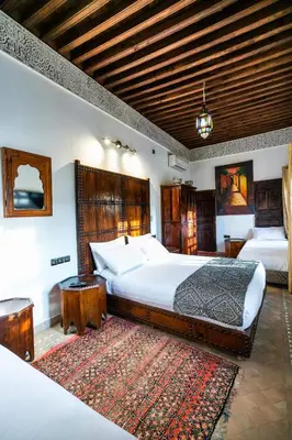 a large bedroom with two beds and a rug at Riad Fes Aicha & SPA in Fès