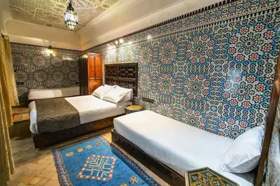 a bedroom with two beds and a wall covered in tiles at Riad Fes Aicha & SPA in Fès
