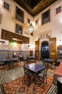 a restaurant with tables and chairs in a room at Riad Fes Aicha & SPA in Fès