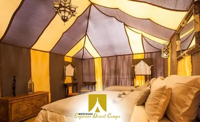 a room with a bed with a sign on it at Superior Desert Camp in Merzouga
