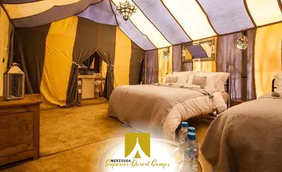 a bedroom with two beds and a tent at Superior Desert Camp in Merzouga