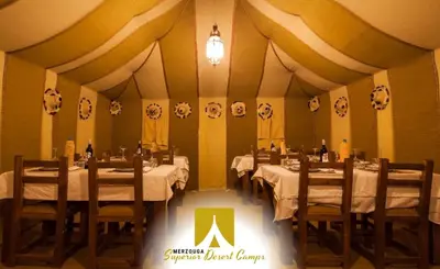 a dining room with tables and chairs in a tent at Superior Desert Camp in Merzouga