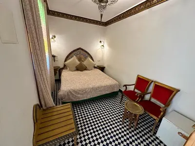 a small bedroom with a bed and two chairs at Riad Shama Fes in Fès
