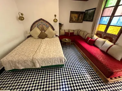 a bedroom with a bed and a couch and a window at Riad Shama Fes in Fès