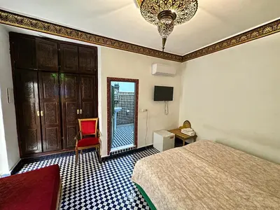 a hotel room with a bed and a red chair at Riad Shama Fes in Fès
