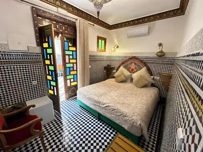 a bedroom with a bed and stained glass windows at Riad Shama Fes in Fès