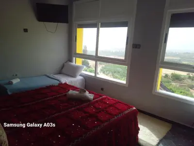 a bedroom with a bed and two windows at Gîte Forest Tagroumte in Azrou