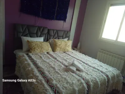 a bedroom with a large bed with two shoes on it at Gîte Forest Tagroumte in Azrou