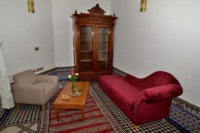 a living room with a red couch and a chair at Riad Al Ansari in Fès