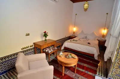 a bedroom with a bed and a couch and a table at Riad Al Ansari in Fès