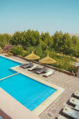 a swimming pool with umbrellas and lounge chairs and a pool at Diar illi in Touama
