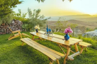 a wooden picnic table with flowers and blue vases on it at Diar illi in Touama