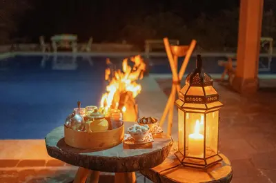 a table with a candle and a lantern next to a pool at Diar illi in Touama