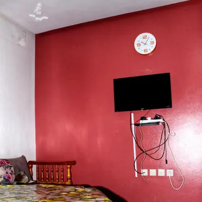 a bedroom with a red wall with a flat screen tv at Appartement Afgo Ouarzazate in Ouarzazate