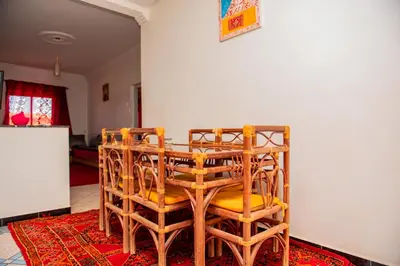 a dining room with a table and chairs on a rug at Appartement Afgo Ouarzazate in Ouarzazate