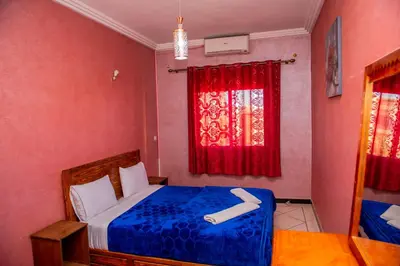 a bedroom with a bed and a window with red curtains at Appartement Afgo Ouarzazate in Ouarzazate