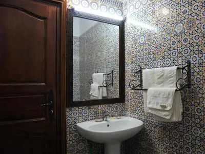 a bathroom with a sink and a mirror and towels at La Kasbah Elkhorbat Muxu Berbere in Asrir