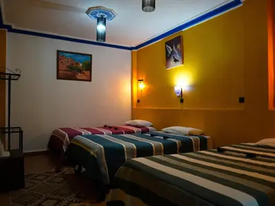 two beds in a room with yellow walls at La Kasbah Elkhorbat Muxu Berbere in Asrir