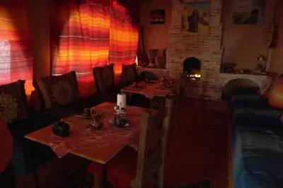 a dining room with two tables and a fireplace at La Kasbah Elkhorbat Muxu Berbere in Asrir