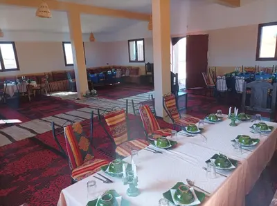 a dining room with tables and chairs in a building at Sahara Bedouin camp in Mhamid