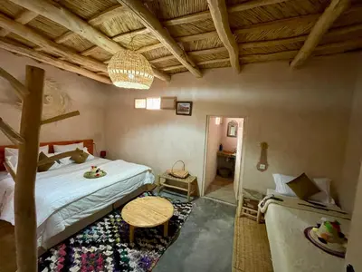 a bedroom with a bed and a table in a room at Maroc des Merveilles - Chez L'habitant in Kalaat MGouna