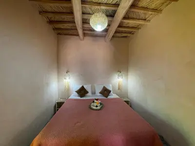a bedroom with a large bed with a red blanket at Maroc des Merveilles - Chez L'habitant in Kalaat MGouna