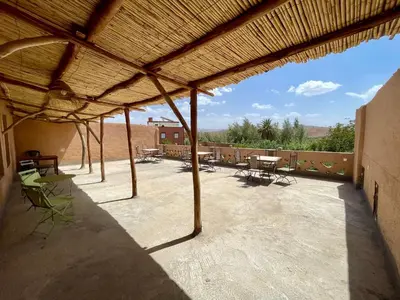 a patio with a roof with tables and chairs at Maroc des Merveilles - Chez L'habitant in Kalaat MGouna