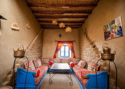 a living room with a red couch and blue chairs at Dar Duna in Hassilabied