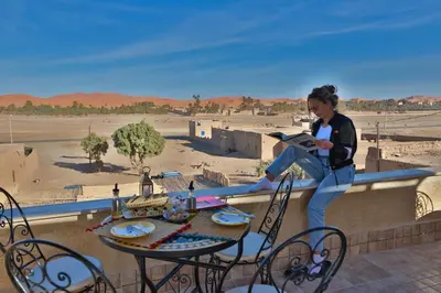 a woman sitting on a wall reading a book at Dar Duna in Hassilabied