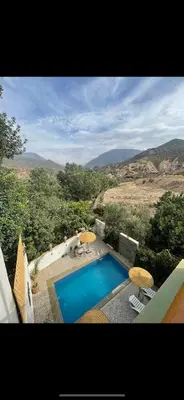 a swimming pool with chairs and umbrellas next to at DAR TAWJA in Asguine