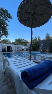 a group of white lounge chairs with an umbrella at DAR TAWJA in Asguine