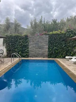 a swimming pool with blue water in front of a hedge at DAR TAWJA in Asguine