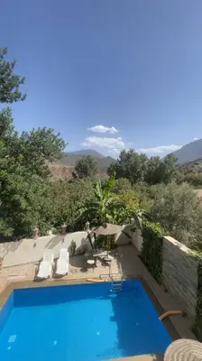 a swimming pool with two lawn chairs and a swimming pool at DAR TAWJA in Asguine