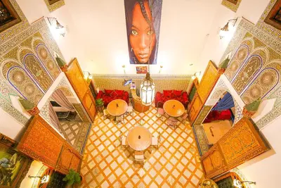 an overhead view of a lobby with tables and a face on the wall at Riad Sahraui in Fès