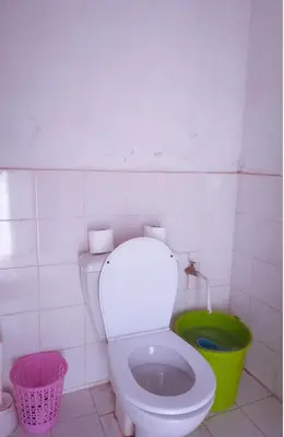 a bathroom with a toilet and a green bucket at Camp Cheri Beri in Mhamid