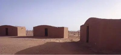 a group of small buildings in the desert at Camp Cheri Beri in Mhamid