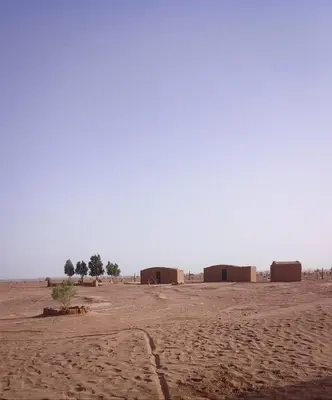 a desert with a group of huts in the distance at Camp Cheri Beri in Mhamid