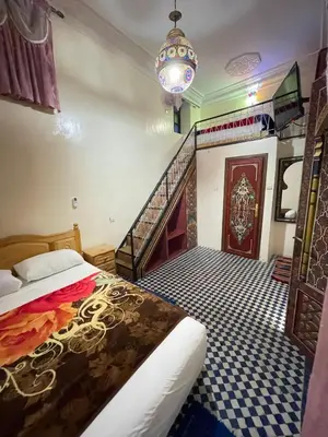 a bedroom with a bed and a staircase and a chandelier at Dar Atlantic in Fès