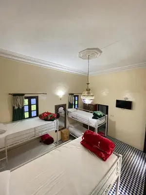 a room with three beds and a chandelier at Dar Atlantic in Fès