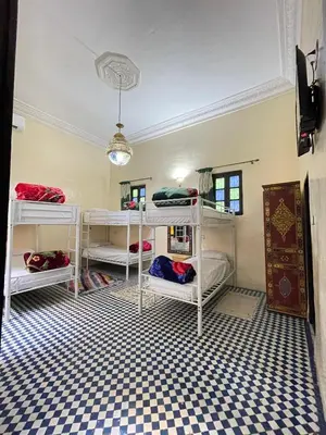 a room with white bunk beds on a checkered floor at Dar Atlantic in Fès