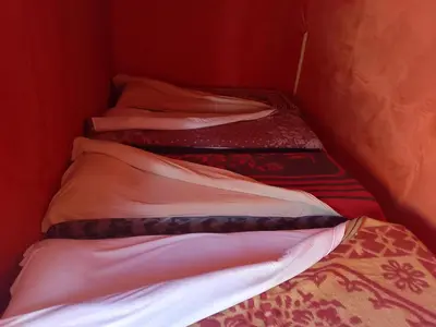 a group of three beds in a small room at Travel Oasis Merzouga Camp in Merzouga