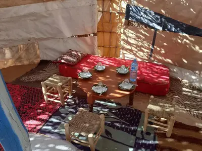 a room with a table and chairs and a red suitcase at Travel Oasis Merzouga Camp in Merzouga