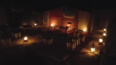 a room with candles and chairs in the dark at Travel Oasis Merzouga Camp in Merzouga