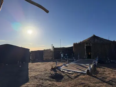 a dirt yard with a building and a basketball court at Travel Oasis Merzouga Camp in Merzouga