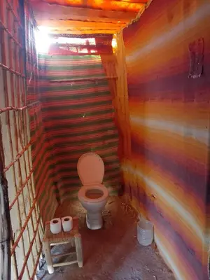 a bathroom with a toilet in a wooden wall at Travel Oasis Merzouga Camp in Merzouga