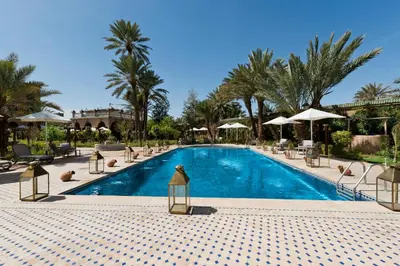 a swimming pool with chairs and umbrellas at a resort at OZ Palace Ouarzazate & SPA in Ouarzazate