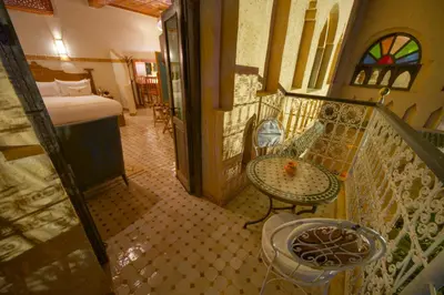 a room with a balcony with a bed and a table at OZ Palace Ouarzazate & SPA in Ouarzazate