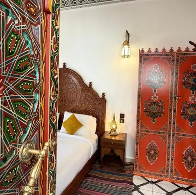 a bedroom with a bed and a red door at Riad Fes Madaw in Fès