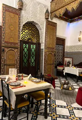 a dining room with a table and chairs and a door at Riad Fes Madaw in Fès